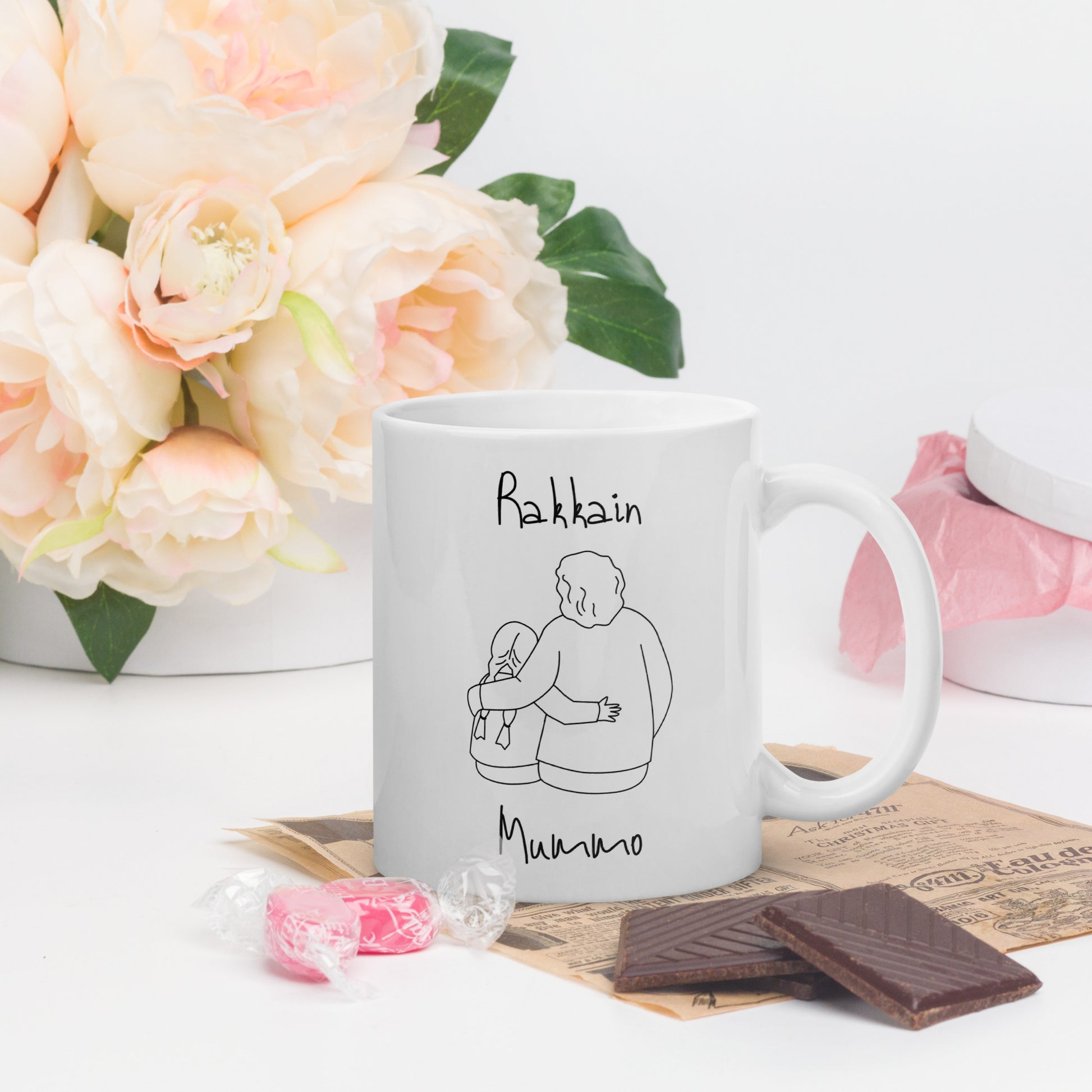 Rakkain mummo muki, jossa piirros mummosta ja lapsesta, taustalla kukkia ja suklaata