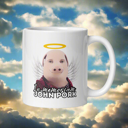 John Pork muki, jossa on enkeli ja teksti 'In memoriam' humoristisella ilmeellä